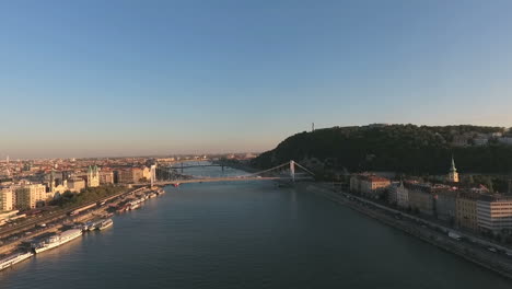 Aerial-shot-of-Budapest,-approaching-the-Gellert-Mountain,-with-the-statue-of-Liberty,-showing-the-Petofi,-and-the-Szabadsag-Bridge