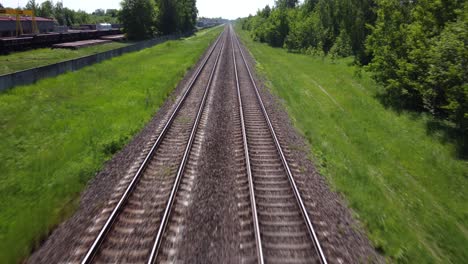 Endless-train-tracks-in-vivid-green-landscape,-fast-flying-over-rails