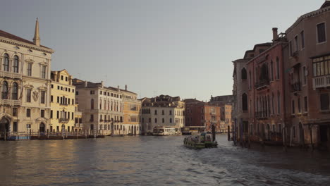 Wide-shot-of-a-Small-boat-cruising-through-morning-Canal-Grande-in-Venice,-Italy