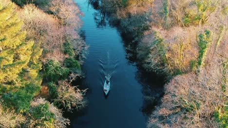 Aerial-shot-boat-driving-along-river-in-Autumn