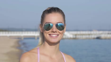 Portrait-of-a-smiling-and-beautiful-blonde-woman-at-the-beach-on-a-sunny-day