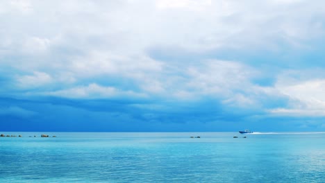 Ein-Schnellboot,-Das-An-Einem-Hellen-Sonnigen-Tag-Mit-Blauem-Himmel-Und-Wolken-Im-Hintergrund-Durch-Die-Wasser-Der-Malediven-Rauscht---Weite-Schwenkaufnahme