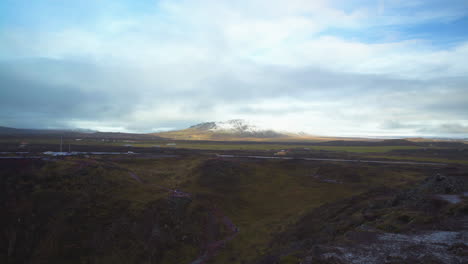 Distant-mountain-in-Iceland-under-cloudy-sky-with-far-away-vehicles-passing-by