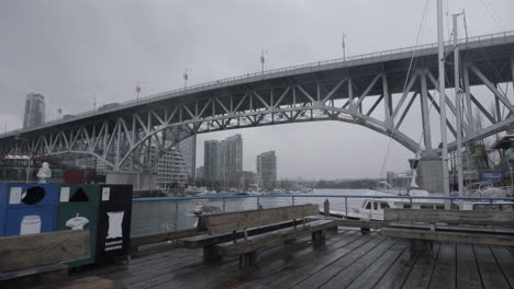 Wide-shot-of-Granville-island-boardwalk-and-bridge-on-cloudy-day