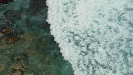 Ocean-waves-rolling-in-to-shore-from-a-bird-eye-view-showing-reef-and-rocks