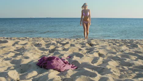 Schöne-Blonde-Frau-Im-Bikini-Geht-An-Einem-Windigen-Tag-Aus-Dem-Wasser-An-Den-Strand