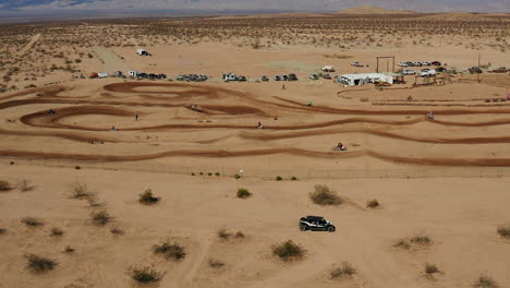 Aerial-view-of-motorcycles-racing-on-a-dirt-track-in-Mojave-Desert,-SLOW-MOTION