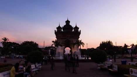 Monumento-Patuxai-Iluminado-Al-Atardecer,-Vientiane-Con-Gente-En-Primer-Plano