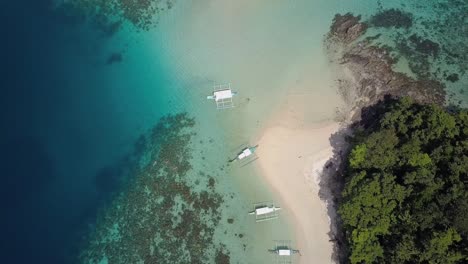 Luftaufnahme-Des-Weißen-Sandstrandes-Auf-Der-Tropischen-Insel-Mit-Traditionellen-Philippinischen-Booten-Auf-Dem-Perfekten-Blauen-Wasser-Auf-Den-Philippinen---Kameraverfolgungssockel-Nach-Unten