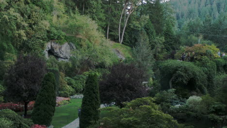 Camera-pans-over-the-intricate-Butchart-Gardens-in-British-Columbia,-Canada-revealing-stunning-flowerbeds,-landscaping,-plant-life,-and-people-walking-through