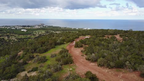 Aerial-drone-shot-of-the-Akamas-Peninsula-of-Cyprus-in-Paphos-following-a-dirt-path-high-in-the-hills-with-the-sea-and-cloudy-sky-in-the-distance