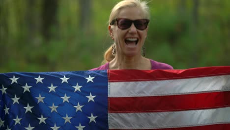 Closeup-of-pretty,-blonde-woman-holding-up-an-American-flag-and-motioning-“yes”-with-her-head