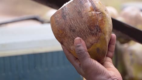 Man-prepares-coconut-water-with-big-knife,-it-is-an-exquisite-and-healthy-drink,-close-up-shot-in-slow-motion