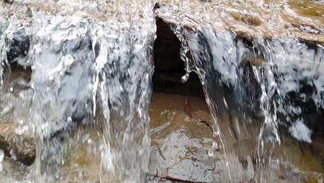 Fließender-Wasserfall-Aus-Einem-Bergquellwasserstrom,-Der-Riesige-Sandsteinfelsen-Mit-Grünem-Moos-Hinunterläuft,-Kristallklares-Trinkwasser,-Meditiert-Ruhige-Und-Friedliche-Zeitlupenaufnahmen