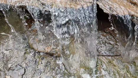 Fließender-Wasserfall-Aus-Einem-Bergquellwasserstrom,-Der-Riesige-Sandsteinfelsen-Mit-Grünem-Moos-Hinunterläuft,-Kristallklares-Trinkwasser,-Meditiert-Ruhige-Und-Friedliche-Zeitlupenaufnahmen