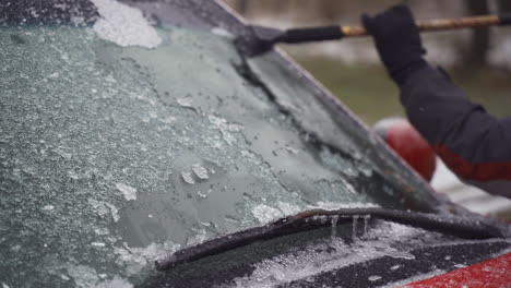 Man-cleaning-and-scraping-ice-from-car-windshield-in-snow-slowmo