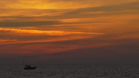 Einsame-Bootssilhouette,-Die-Sich-Im-Indischen-Ozean-Von-Links-Nach-Rechts-Bewegt,-Mit-Spektakulärem-Buntem-Himmel-Nach-Sonnenuntergang,-Goa,-Indien