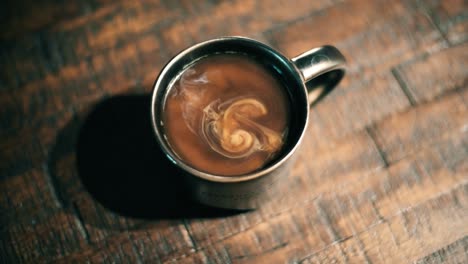 Milk-swirling-in-a-coffee-cup-on-a-kitchen-table