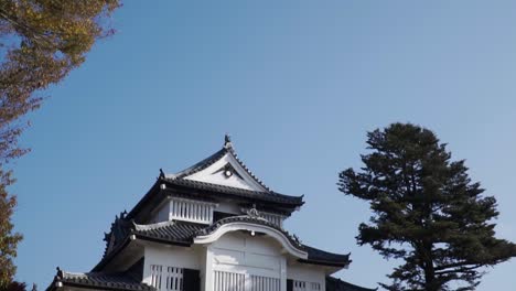 Fast-pan-up-over-beautiful-historic-Bitchu-Matsuyama-castle-with-bright-blue-sky-and-old-Japanese-tourist-walking-in-front-of-it