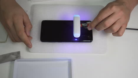 Taschenlampe-Fährt-über-Einen-Smartphone-Bildschirm,-Um-Den-Kleber-Zu-Trocknen