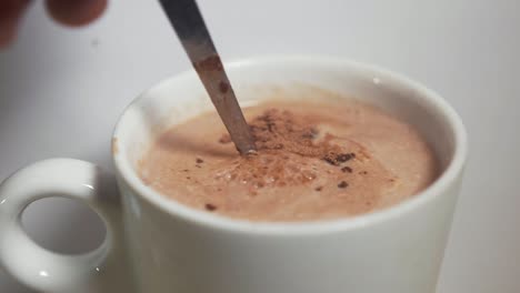 Putting-spoon-of-hot-chocolate-powder-into-mug-of-hot-milk-and-stirring