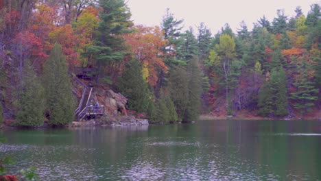 Zoomed-in-pan-over-lake-of-hills-with-board-walks-and-people-hiking-in-the-forest-with-lots-of-fall-colours