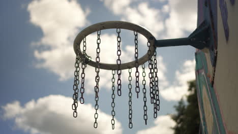 Wind-Bewegende-Ketten-Eines-Basketballrings-Mit-Blauem-Himmel-Im-Vordergrund