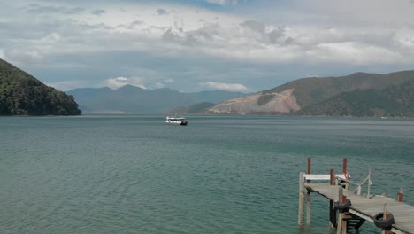 Boat-on-the-sea-in-Marlborough-Sounds,-New-Zealand-with-mountains-in-background---Aerial-Drone
