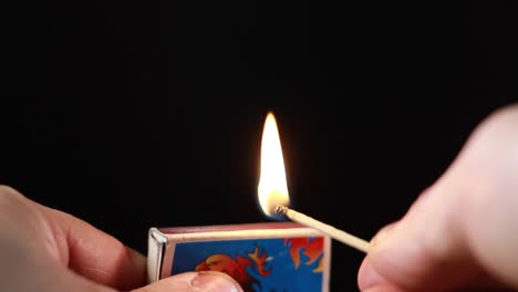 Lighting-A-Match-From-Matchbox-On-Black-Background