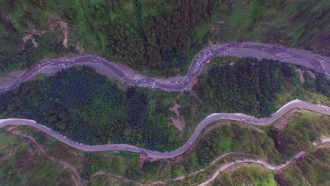 Zigzag-road-top-view,-Kahmir,-India,-Traffice-is-going-on,-Big-forest-and-green-trees,-tow-zigzag-road-and-a-river-view-from-maximum-hieght,-camera-moiving-from-top-with-mountaind-and-roads