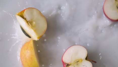 Slices-of-apple-falling-into-milky-water-with-splashes-in-slowmotion