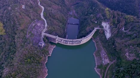 Top-Down-View-Of-Jiguey-Dam,-arch-gravity-dam-on-the-Nizao-River,-San-José-de-Ocoa-Province-of-the-Dominican-Republic---aerial-drone-shot