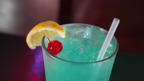 Ein-Eisblauer-Cocktail,-Garniert-Mit-Einer-Zitronenscheibe-Und-Marachino-Kirsche,-Nahaufnahme-4k