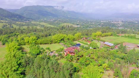 Aerial-view-showing-little-village-surrounded-by-green-landscape-and-mountains-in-Jarabacoa,Dominican-Republic