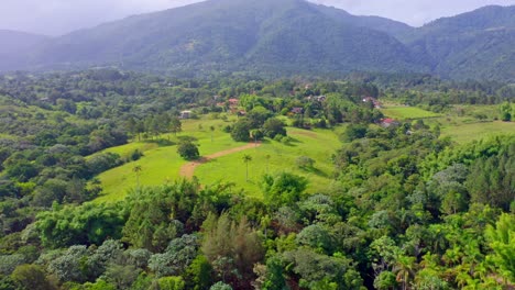 Filmischer-Luftflug-über-Grünen-Regenwald-Und-Dominikanische-Alpen-Im-Hintergrund