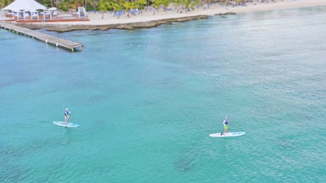 Tourists-paddle-sup-on-caribbean-sea-of-Dominicus-beach,-Dominican-Republic