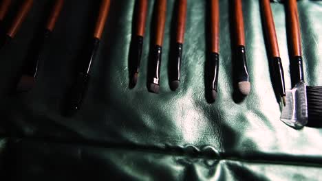 wooden-and-metal-brown-set-of-make-up-brushes-on-green-shiny-cover-background-with-sliding-movement