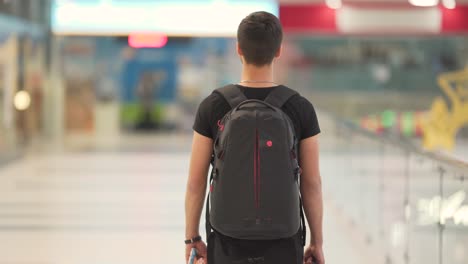 Young-man-with-a-black-backpack-walking-in-the-mall