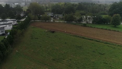 Drone-Ariel-View-of-Amish-Farm-Lands-and-Amish-Farmer-Harvesting-in-Fog