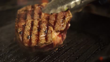Zeitlupe---Zange-Dreht-Steak-Um,-Das-Auf-Einer-Grillpfanne-Kocht---Nahaufnahme-Detail