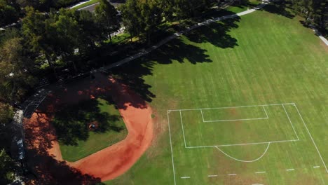 Aerial-rotation-over-a-community-park-from-the-soccer-and-baseball-field-to-the-community-pool