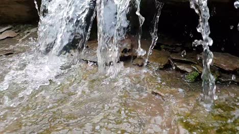 Fließender-Wasserfall-Aus-Einem-Bergquellbach,-Der-Riesige-Sandsteinfelsen-Mit-Grünem-Moos-Hinunterläuft,-Kristallklares-Trinkwasser,-Meditiert-Ruhige-Und-Friedliche-Zeitlupenaufnahmen