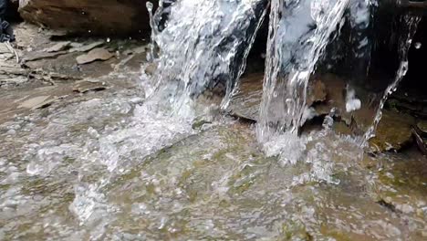 Fließender-Wasserfall-Aus-Einem-Bergquellbach,-Der-Riesige-Sandsteinfelsen-Mit-Grünem-Moos-Hinunterläuft,-Kristallklares-Trinkwasser,-Meditiert-Ruhig-Und-Friedlich,-Ruhige-Zeitlupe