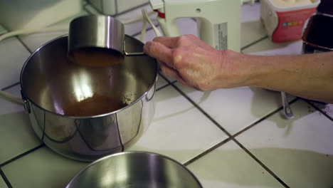 Ein-Koch-Schöpft-Schokoladenpulver-Und-Mehl-In-Eine-Rührschüssel-Aus-Metall,-Während-Er-In-Der-Küche-Einen-Veganen-Schokoladenkuchen-Herstellt