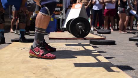 Man-drops-barbell-with-weights-on-the-ground-after-finishing-the-last-repetition-at-a-CrossFit-competition