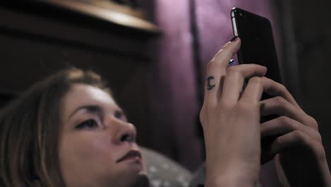 Low-view-of-beautiful-woman-with-nose-piercing-wasting-time-surfing-the-internet-on-smartphone