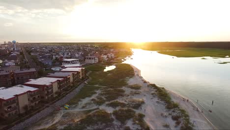 Drone-flying-away-from-sun-over-waterway-near-inlet
