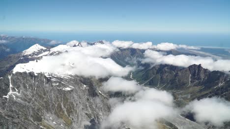 SLOWMO---Aerial-shot-from-plane-scenic-flight-over-west-coast-Franz-Josef-Glacier,-Aoraki-Mount-Cook,-National-Park-with-clouds,-snowcapped-rocky-mountains-and-ocean-in-background