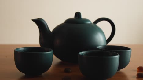 minimal-background-of-a-green-japanese-tea-set-with-steam-coming-out-of-the-cups,-on-a-wooden-table,-with-some-stones-around