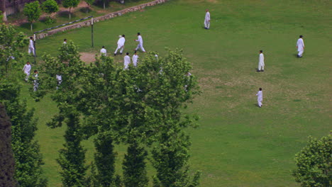 Peshawar,-Pakistán,-Estudiantes-Jugando-Fútbol-Vista-Aérea-Desde-Los-árboles,-Los-Estudiantes-Están-En-Uniformes-Blancos-Shalwar-Kameez